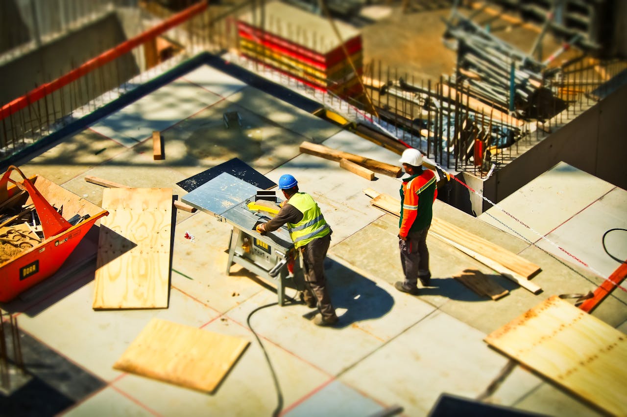 services-06 Construction workers engaging in tasks at an outdoor building site with safety hats and equipment.