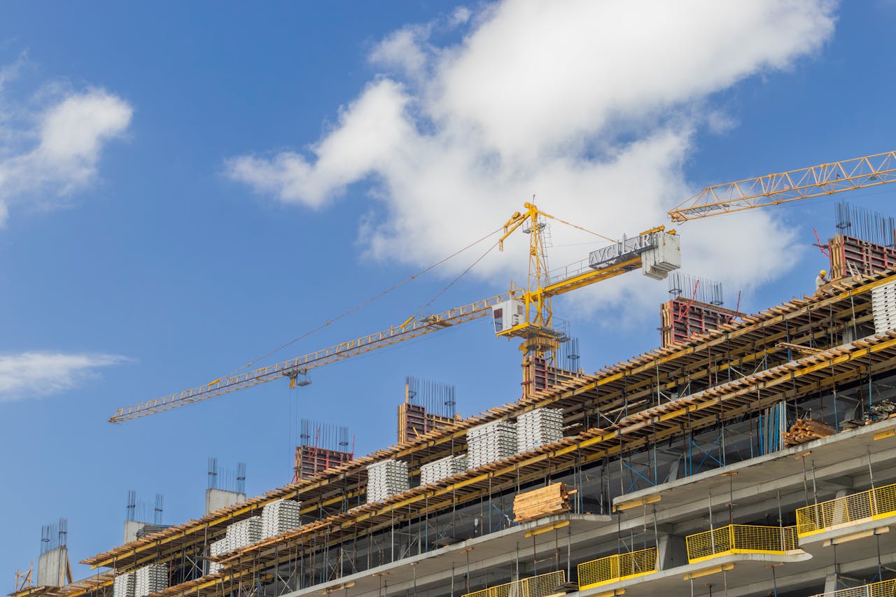 about-us A modern construction site with cranes against a clear blue sky, showcasing urban development.
